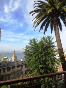 a view of a city from a balcony with a palm tree at Gervasoni Hotel Boutique in Valparaíso