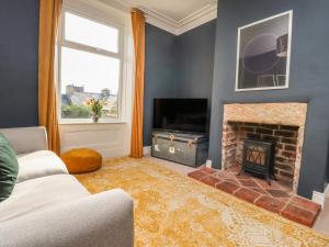 a living room with a fireplace and a television at Castlewood Cottage in Skipton