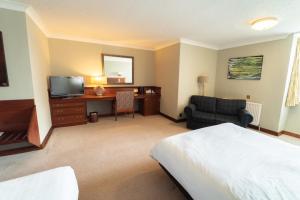 a hotel room with a bed and a desk and a television at Littlebury Hotel in Bicester