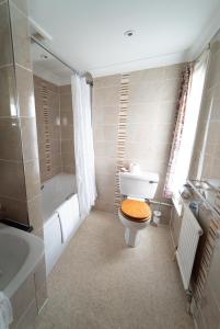 a bathroom with a toilet and a bath tub at Littlebury Hotel in Bicester