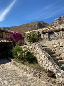 a stone house with a stone wall and some plants at La Casina in Siculiana