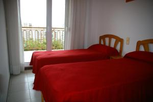 1 dormitorio con 2 camas con sábanas rojas y ventana en Costa Brasil Superior Orangecosta, en Benicàssim