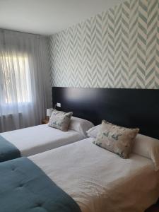 オ・ペドロウソにあるNoja rooms 1のストライプの壁紙が貼られたホテルの部屋にベッドが2つある