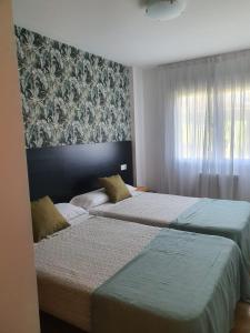 オ・ペドロウソにあるNoja rooms 1の壁画のあるベッドルーム1室(ベッド2台付)