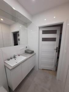 a white bathroom with a sink and a mirror at Apartament Rodzinny Baltic Park Stegna in Stegna
