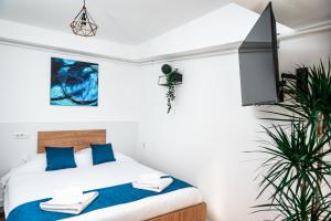 a bedroom with a bed with blue pillows and a tv at Puzzle Apartaments&Studios in Craiova +102 photos