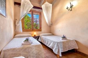 two beds in a room with a window at Country house with amazing pool in a beautiful rural setting in Campanet +41 photos