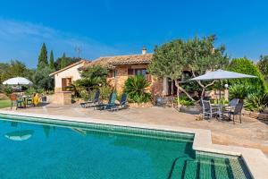 a villa with a swimming pool in front of a house at Country house with amazing pool in a beautiful rural setting in Campanet
