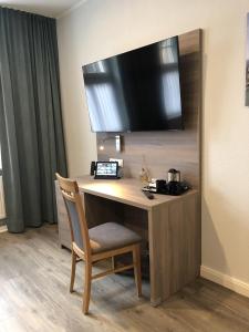 a desk in a hotel room with a chair and a television at AKZENT Hotel Restaurant Roter Ochse Rhens bei Koblenz in Rhens