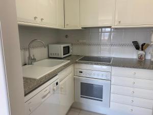 a white kitchen with a sink and a microwave at BLAU Bonito Duplex con Terraza in Calella de Palafrugell