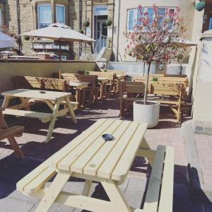 un groupe de tables de pique-nique et de bancs sur une terrasse dans l'établissement Hotel No 8, à Skegness