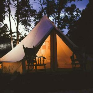 uma tenda com duas cadeiras em frente em Pop-up glamping - Buurvrouws' Belltentje 2-4 pers em Zuna