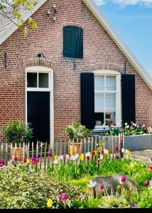 une maison avec une clôture et des fleurs devant elle dans l'établissement Erve de Kippe. Vrij maar toch dichtbij., à Epse