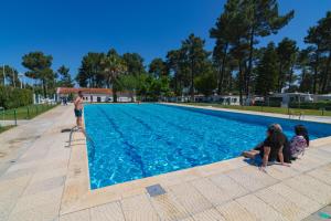 a man and two children sitting next to a swimming pool at Valbom by Campigir in Sesimbra