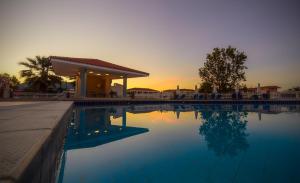 a swimming pool with a sunset in the background at Karras Hotel in Laganas