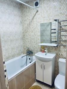 La salle de bains est pourvue d'une baignoire, d'un lavabo et de toilettes. dans l'établissement квартира -студия в центре, à Khmelnytsky
