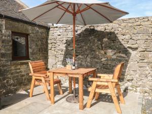 a wooden table with two chairs and an umbrella at Shepherds Retreat in Ashbourne