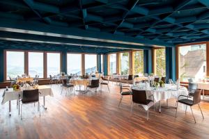 een eetkamer met tafels, stoelen en ramen bij Hotel Gasthaus Hergiswald in Eigenthal