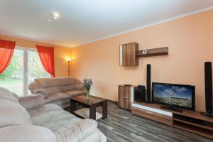 a living room with a couch and a flat screen tv at Dom Wakacyjny Kurnik by Renters in Kołczewo
