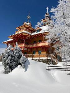 duży drewniany dom w śniegu z pokrytymi śniegiem drzewami w obiekcie Libušín & Maměnka národní kulturní památky w mieście Prostřední Bečva