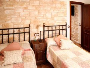 1 dormitorio con 2 camas y pared de piedra en Casa Rural La Tayuela, en Luanco