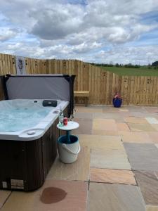 a hot tub on a patio with a wooden fence at Thistle Pod at Ayrshire Rural Retreats Farm Stay Hottub Sleeps 2 in Galston