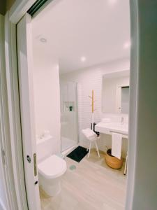 a white bathroom with a toilet and a sink at Maré Viva Bed & Breakfast in Rego da Leirosa