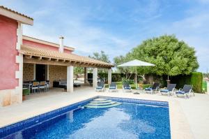una casa con piscina con sedie e ombrellone di YourHouse Can Cuixa Villa a Can Picafort