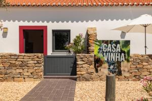 een wit huis met een rode deur en een stenen muur bij Fontes Bárbaras Enoturismo in Entradas