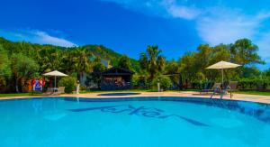 a large swimming pool with a gazebo and umbrella at Mesken Inn Hotel in Göcek