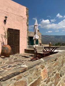 een patio met een tafel en een paraplu en een tafel en een vat bij Lithos Homes in Volissos