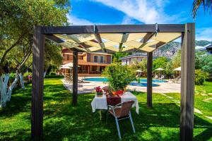 a picnic table under a wooden pergola in a yard at Mesken Inn Hotel in Göcek