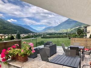 d'une terrasse avec une table, des chaises et des montagnes. dans l'établissement B&B Valtellina Mon Amour, à Piateda