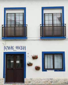 2 fotos de un edificio con puerta y balcón en Quartos Abelha, en Porto Covo