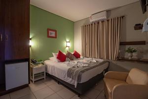 Cette chambre comprend un lit avec des oreillers rouges. dans l'établissement Santa Eliza Eco Resort, à Ribeirão Bonito 243 autres photos