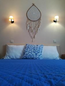 a bedroom with a blue bed with two lights on the wall at Quartos Abelha in Porto Covo