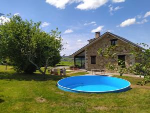 a large blue pool in the grass in front of a house at Casa con gran jardín y piscina en Cabarceno in Villanueva