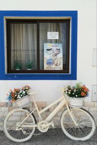 a white bike parked in front of a building with flowers at Quartos Abelha in Porto Covo +27 photos