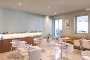 薩羅的住宿－阿洛米皮克羅酒店，餐厅设有白色的桌椅和柜台