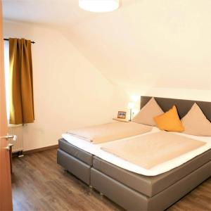 ランゲナルゲンにあるHaus Apfelblüteのベッドルーム1室(大型ベッド1台、オレンジ色の枕付)
