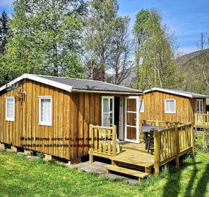 een houten hut met een veranda en een terras bij Camping Chantecler in Luchon