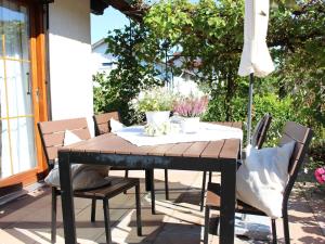a wooden table with chairs and an umbrella on a patio at Haus Apfelblüte in Langenargen