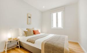a white bedroom with a large bed and a window at Espinho Beach 4 Stays in Espinho