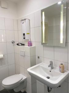 uma casa de banho branca com um lavatório e um WC em Gerresheimer Republic em Düsseldorf