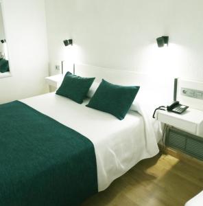 a bedroom with a white bed with green pillows at Hotel Goya in Crevillente