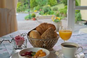 a table with a basket of bread and a glass of orange juice at Hotel Lindenhof in Monschau