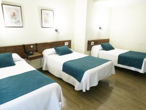 a room with three beds with green and white sheets at Hotel Goya in Crevillente