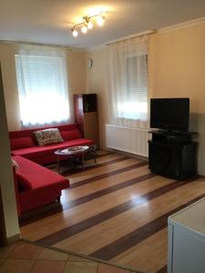 a living room with a red couch and a flat screen tv at 4 Lurkó Apartman Új in Hajdúszoboszló