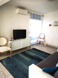 a living room with a flat screen tv and two chairs at Attico LUX in Lido di Ostia