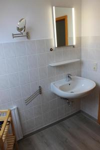 a white bathroom with a sink and a mirror at Gästehaus Sulsdorf - Adults only in Sulsdorf auf Fehmarn